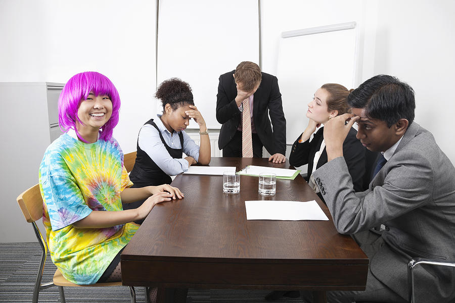 Tired multiethnic businesspeople with colleague in pink wig at meeting Photograph by Moodboard
