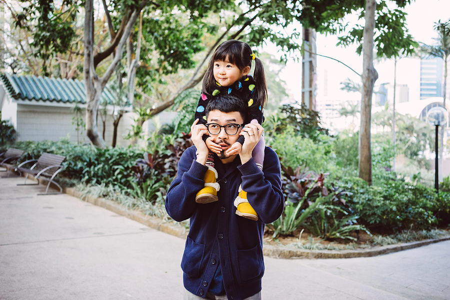 Toddler gilt sitting on dads shoulders in park Photograph by images by Tang Ming Tung