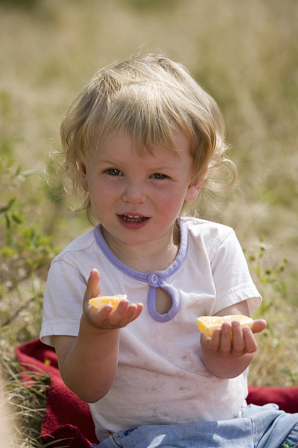 Toddler girl eating fruit Photograph by Comstock Images