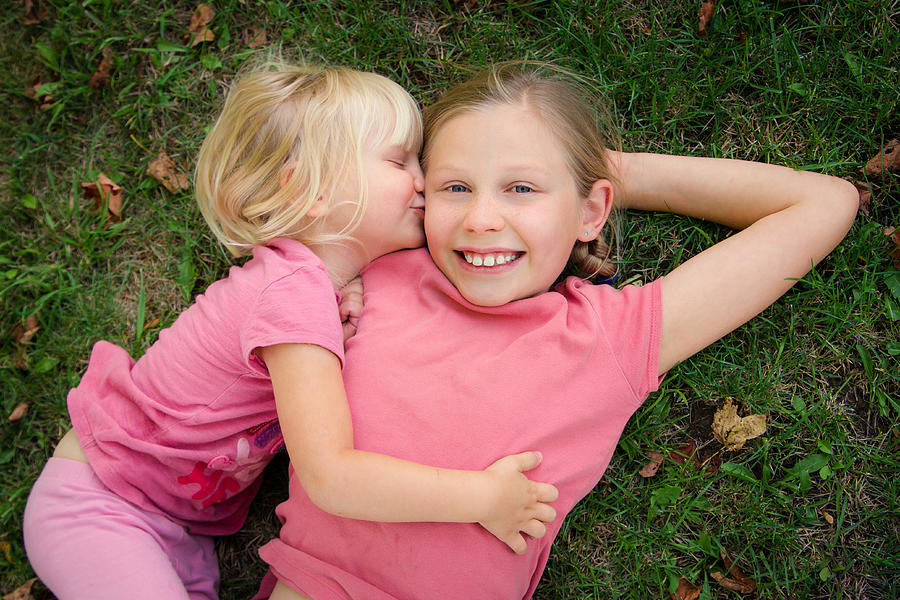 Toddler girl kissing big sister Photograph by Adeena Pentland