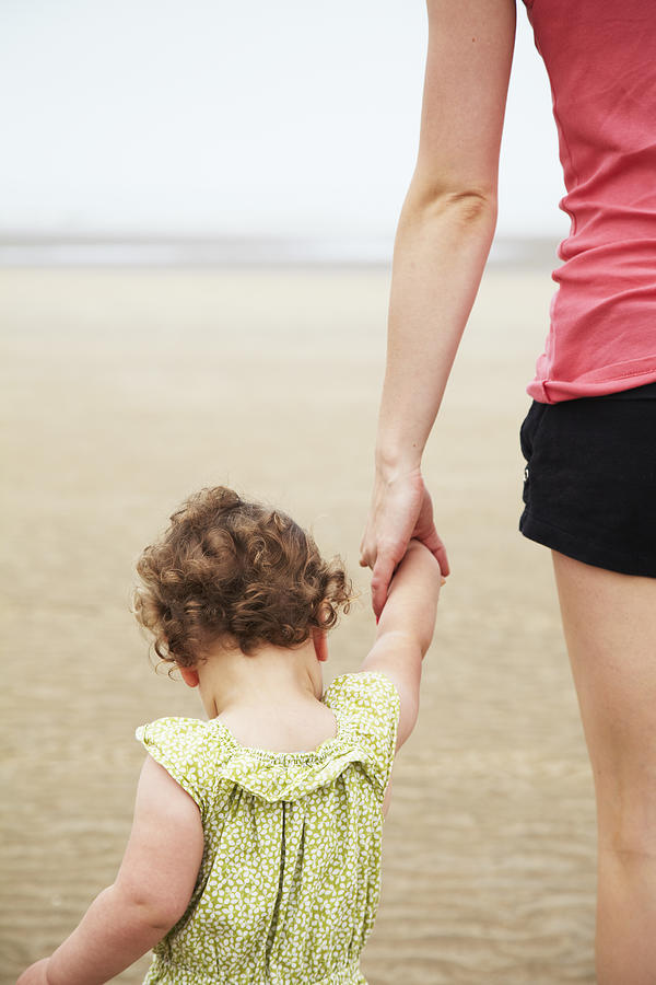 Toddler holding hands on beach Photograph by Ben Richardson