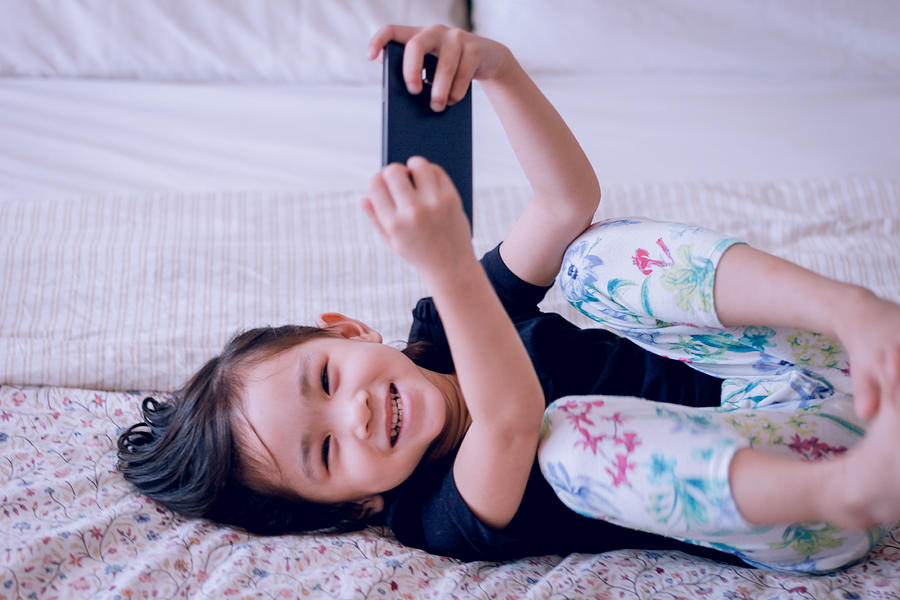 Toddler laughing while watching cartoon on smartphone Photograph by Suphat Bhandharangsri Photography