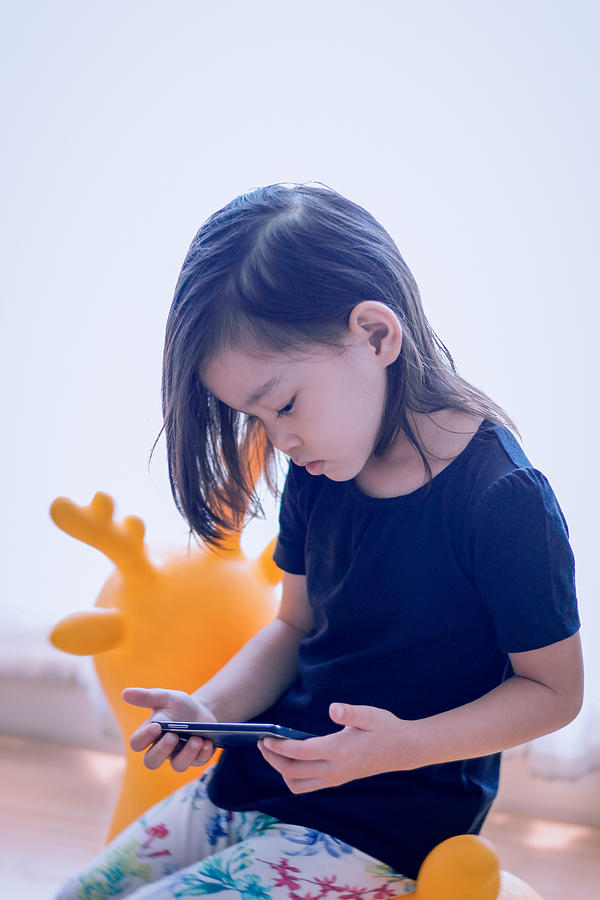 Toddler watching a video clip on yellow deer toy Photograph by Suphat Bhandharangsri Photography