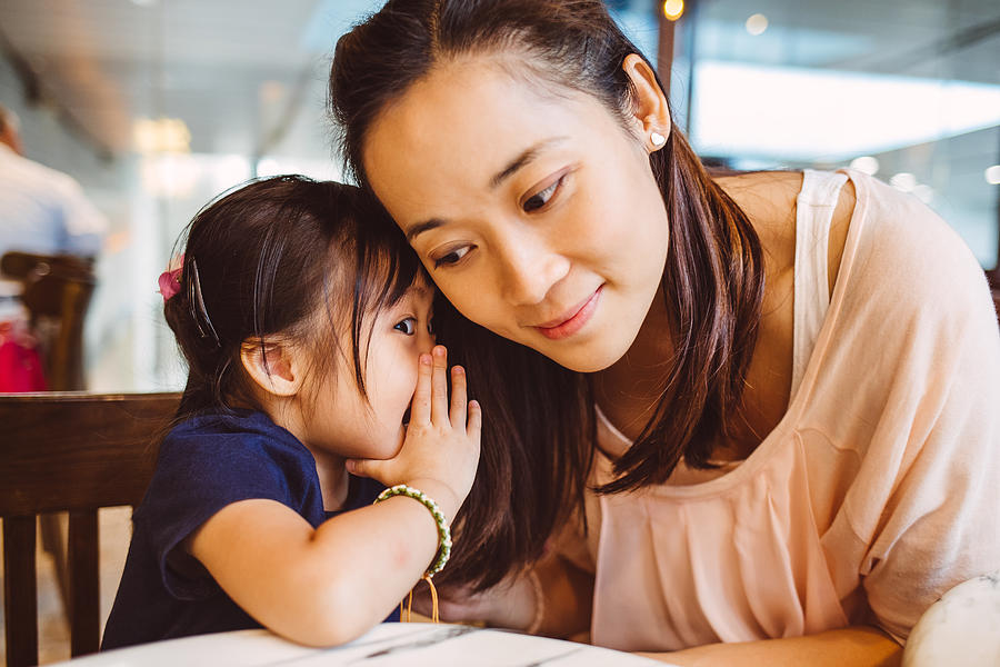 Toddler whispering into moms ear in cafe Photograph by Images By Tang Ming Tung