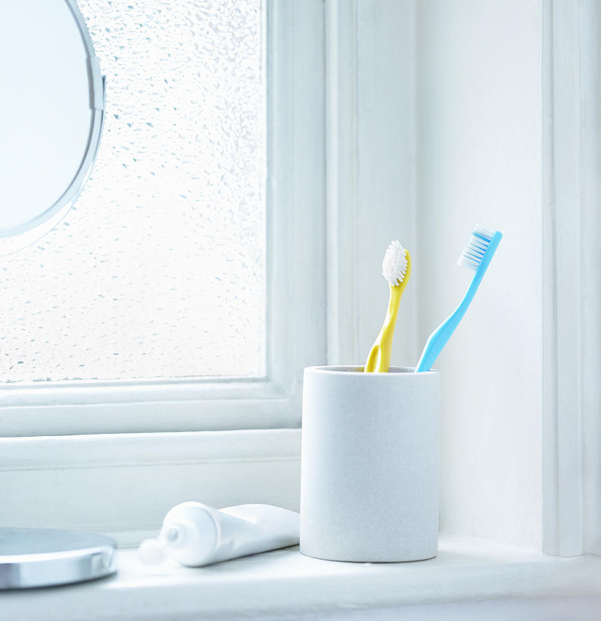 Tooth brushes in cup sitting on bathrrom window Photograph by Dougal Waters