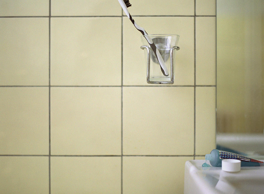 Toothbrush in cup holder next to bathroom sink. Photograph by Matthieu Spohn