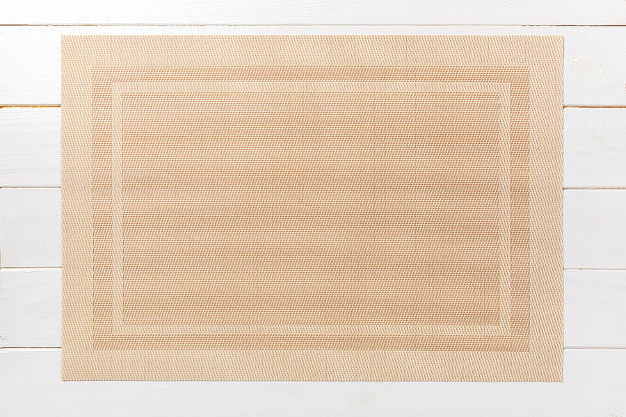 Top view of brown place mat for a dish. Wooden background with empty space for your design Photograph by Mykola Sosiukin