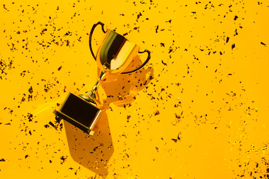 Top view of metallic golden goblet on bright yellow background with sequin. Goal achievement concept. Trendy colors of the year Photograph by Anna Efetova