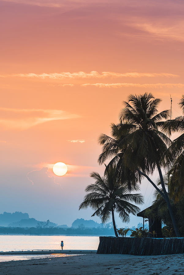 Tourist admiring the sunrise on tropical island Photograph by © Marco Bottigelli