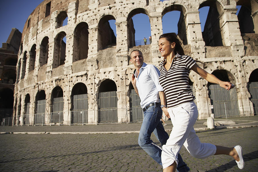 Tourist couple running near coliseum Photograph by Rolf Bruderer
