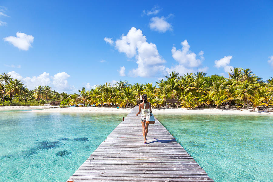 Tourist walking on jetty to tropical island Photograph by Matteo Colombo