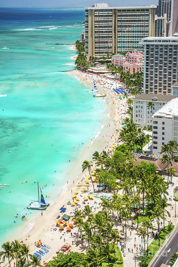 Tourists enjoying vacationing on world famous Waikiki Beach in front of 