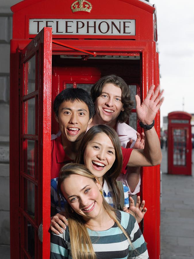 Tourists in a red telephone booth Photograph by Image Source