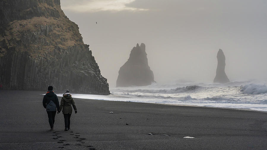 Tourists taking a walk on the Reynisdrangar beach with the seastacks in the background, in the south Photograph by Anges Van der Logt