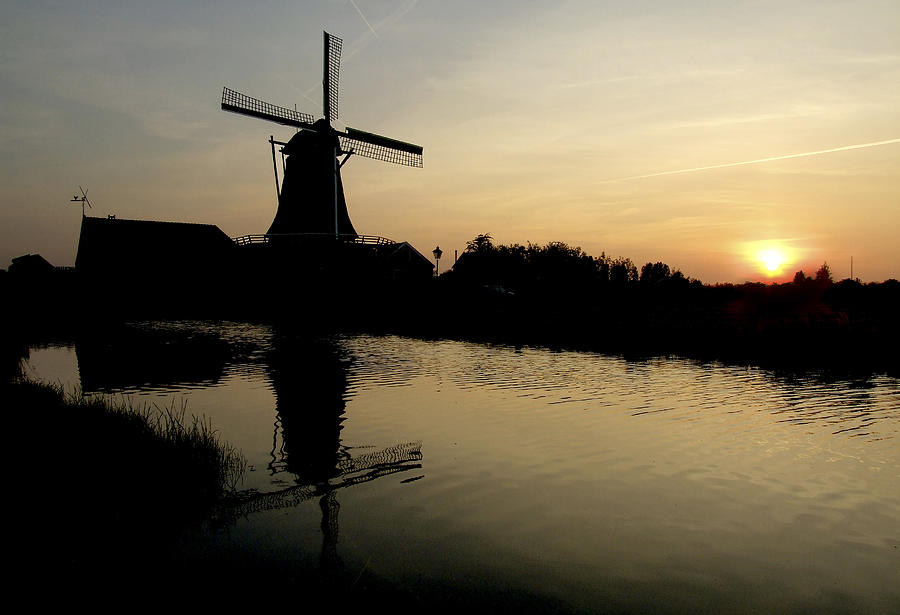 Traditional Dutch windmill on the banks of river Zaan backlighted at sunset in Zaanse Schans, Netherlands Photograph by Photo by Victor Ovies Arenas
