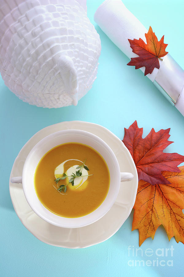 Traditional Thanksgiving pumpkin soup on pale blue table. Photograph by Milleflore Images