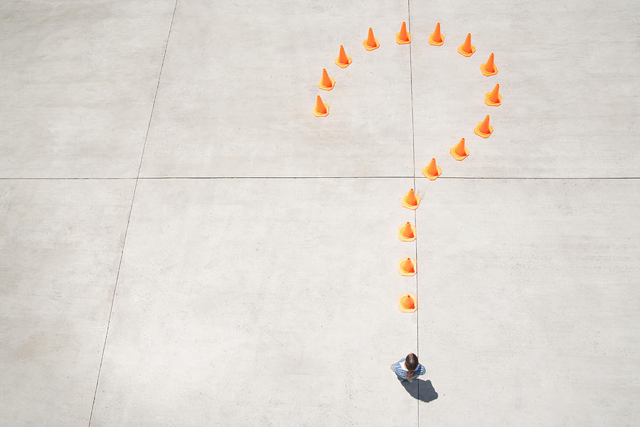 Traffic cones forming question mark with woman at point standing Photograph by Martin Barraud