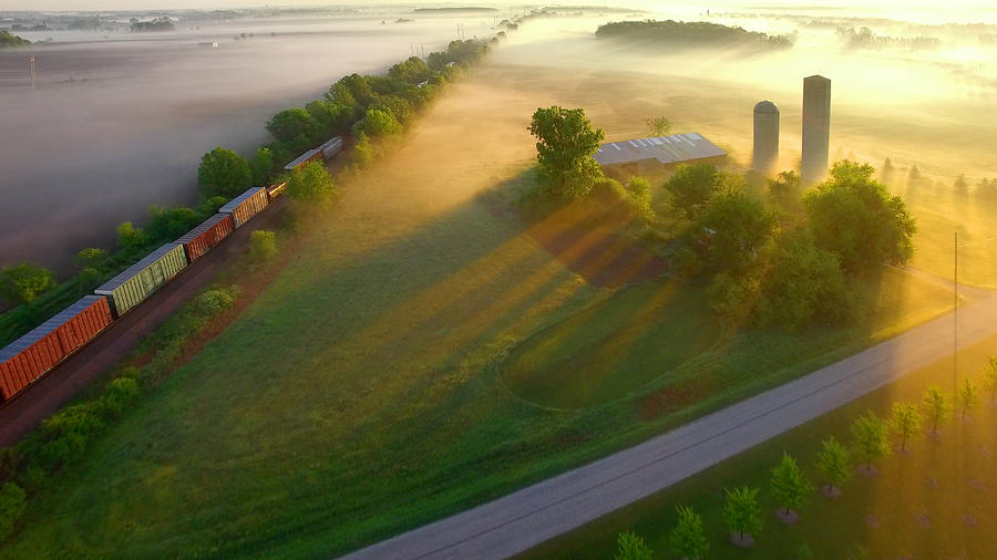 Train rolls through foggy rural landscape at dawn. Photograph by JamesBrey