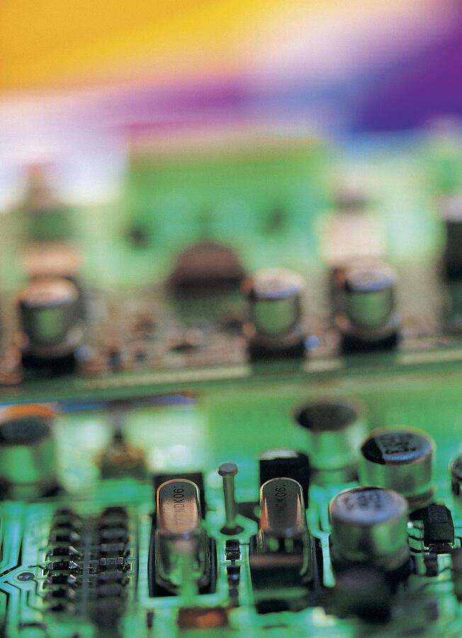 Transistors on a colorfully variegated circuit board Photograph by Chris Knapton