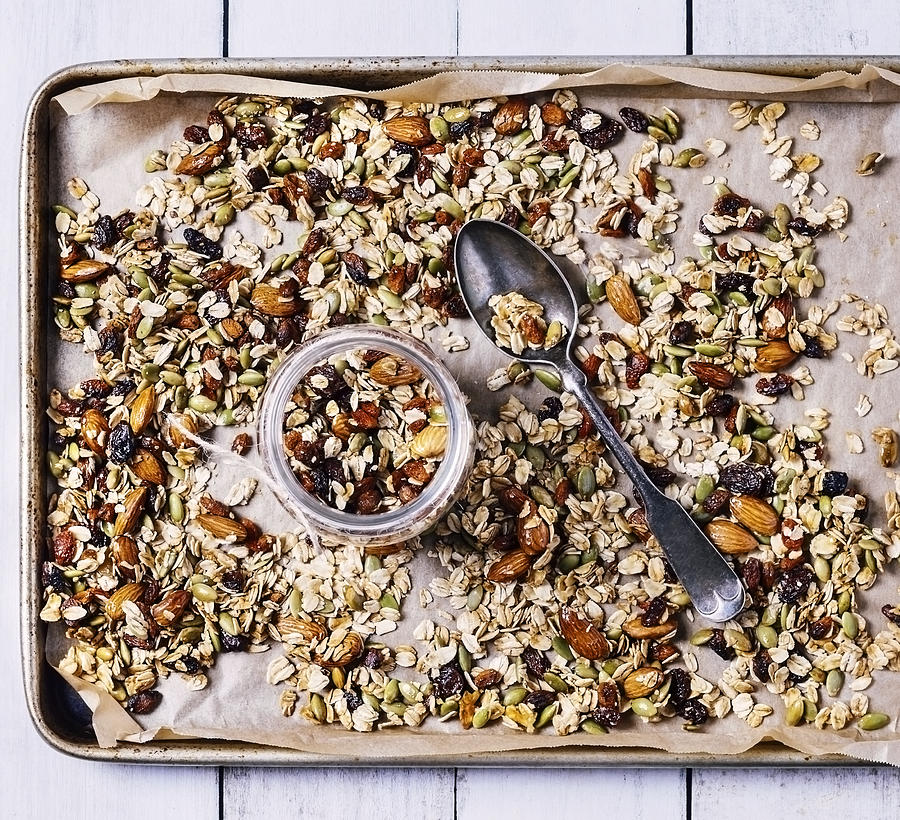 Tray of granola on white, wooden background Photograph by Claudia Totir
