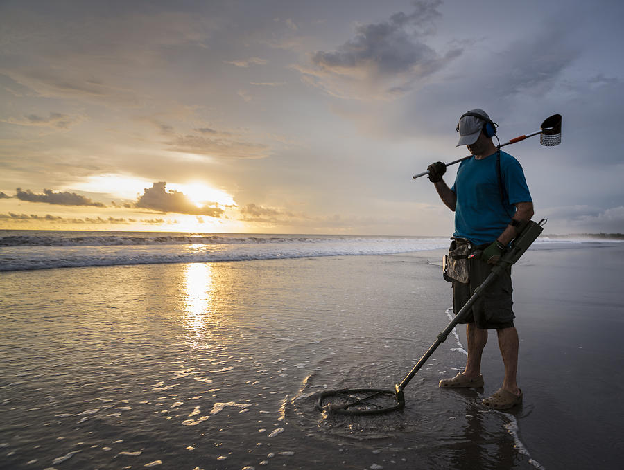 Treasure hunter on the beach with a metal detector Photograph by Joakimbkk