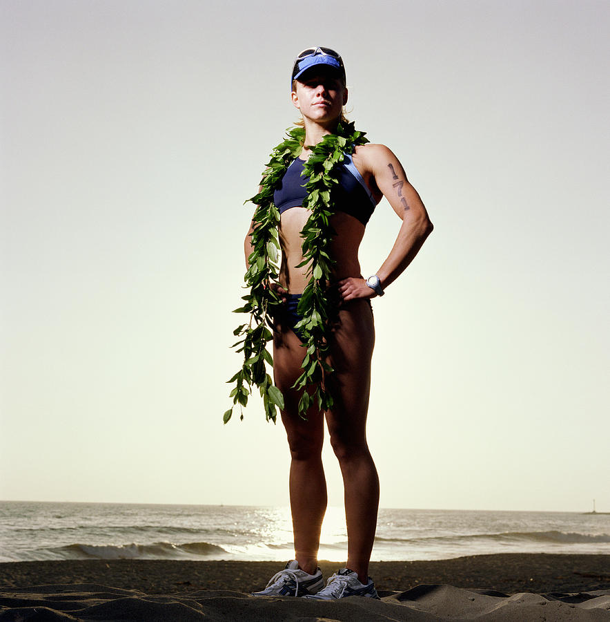 Triathlete wearing ti leaf lei, standing on beach, portrait Photograph by Mike Powell