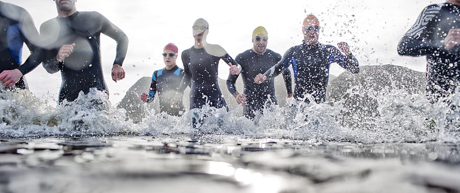 Triathletes emerging from water Photograph by Caia Image