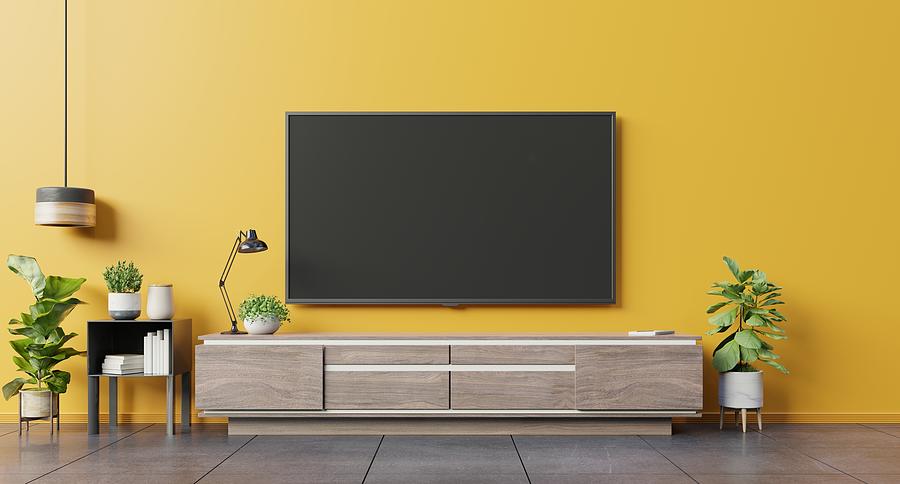 TV on cabinet in modern living room on yellow wall background. Photograph by Vanit Janthra