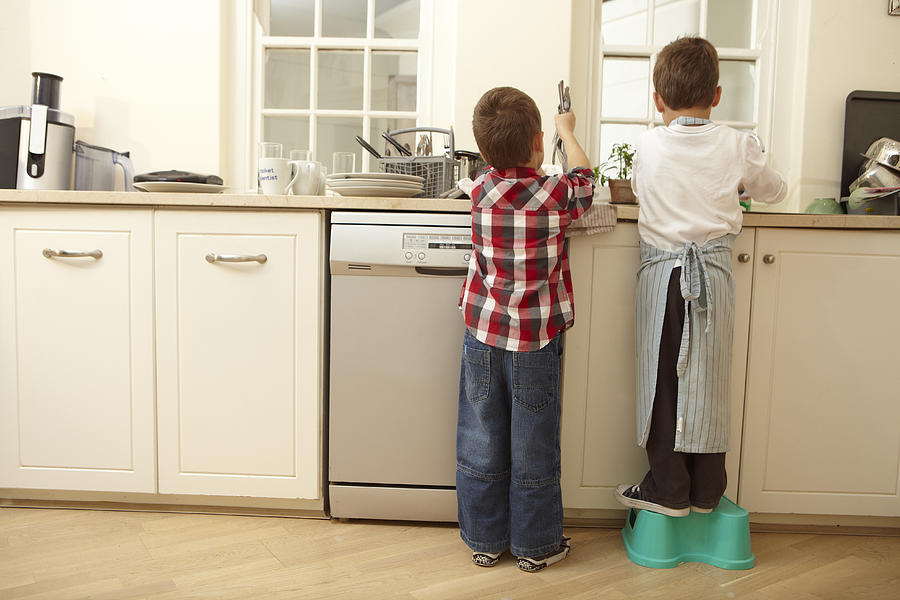Twin boys washing dishes after dinner Photograph by Smile