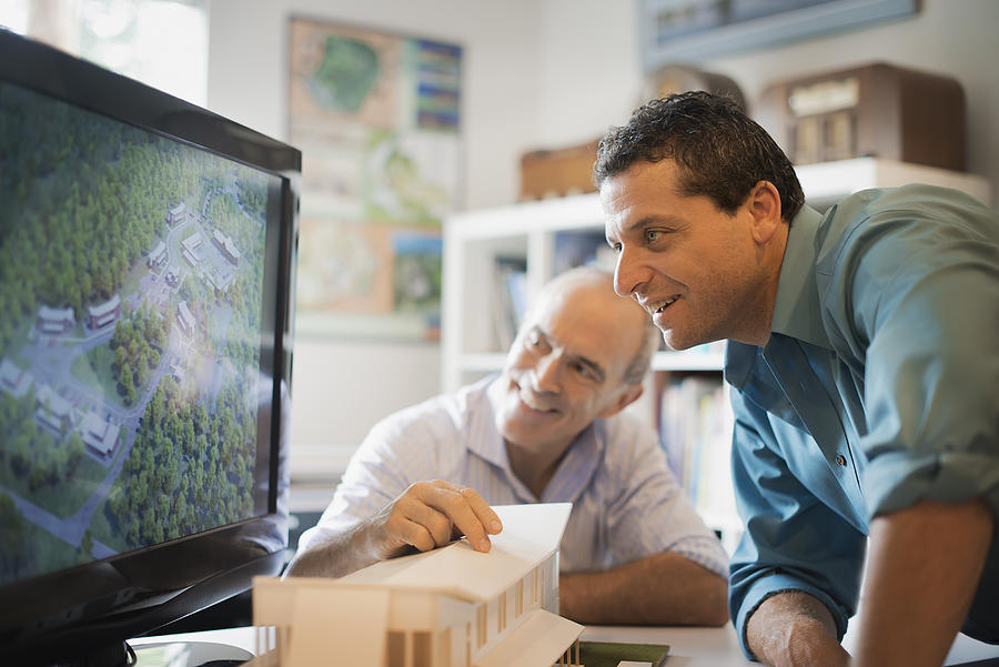 Two architects working on a green construction project, using computer technology. Scale model of a building. Computer design. Photograph by Mint Images - Tim Pannell