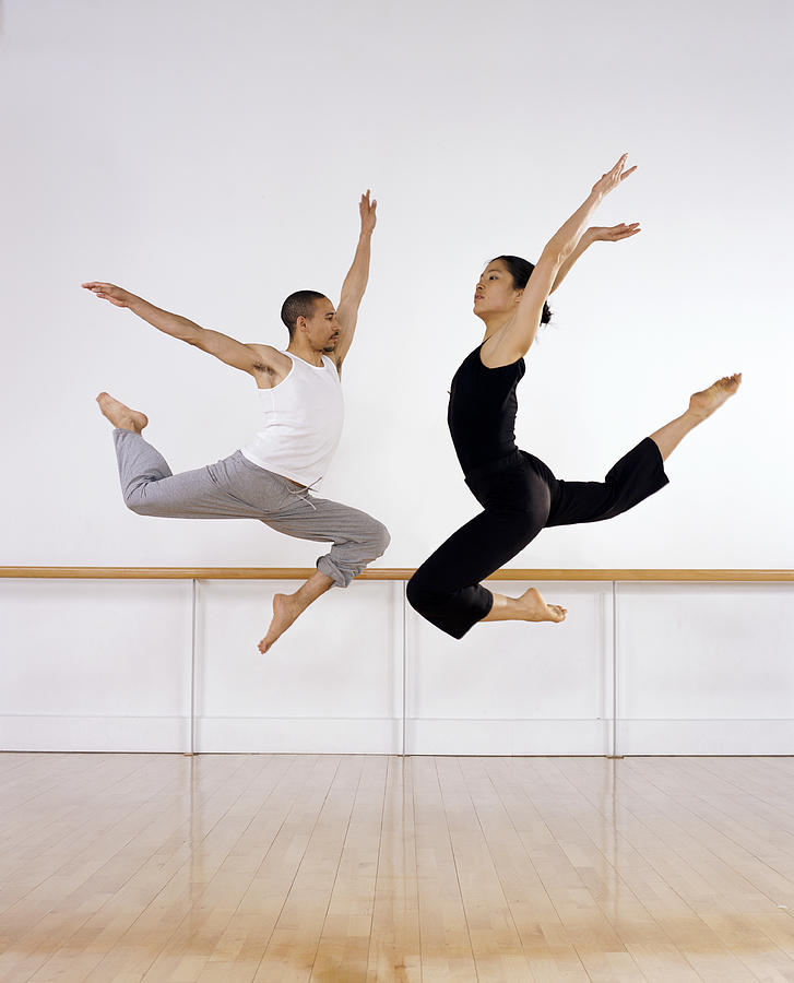 Two Ballet Dancers Jumping Mid Air With Their Arms Raised and Looking Face to Face Photograph by Nick White