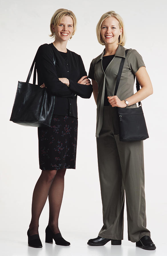 Two Beautiful  Young Caucasian Women With Shoulder Length Blond Hair Dressed In Businees Attire And Purses Standing Together Smiling Into The Camera Photograph by Photodisc