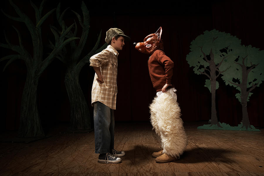 Two boys (9-11) acting on stage, one boy confronting other as bad wolf Photograph by Adam Taylor