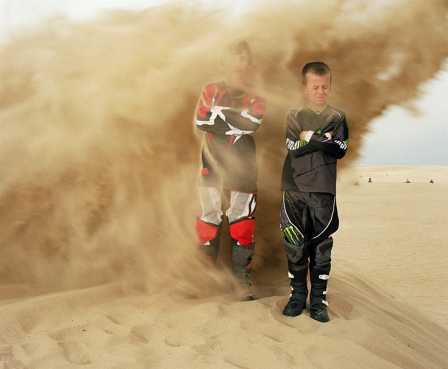 Two boys being blasted with sand from motorcycle. Photograph by Pete Starman