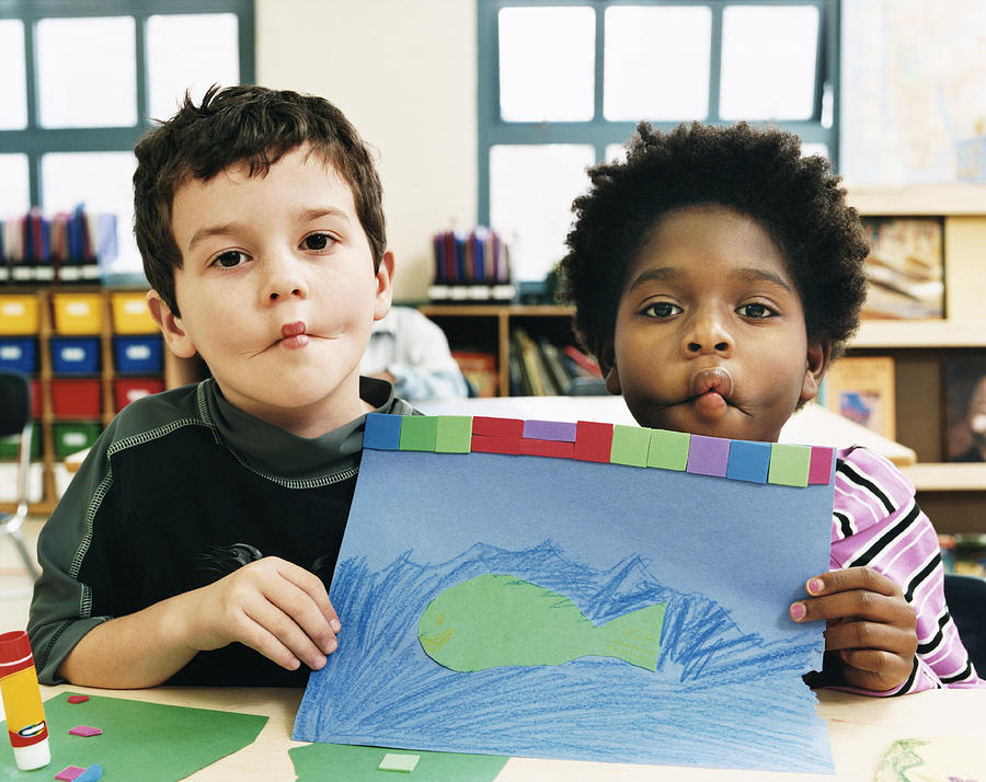 Two Boys Showing a Drawing in a Classroom and Pulling Funny Faces Photograph by Digital Vision.