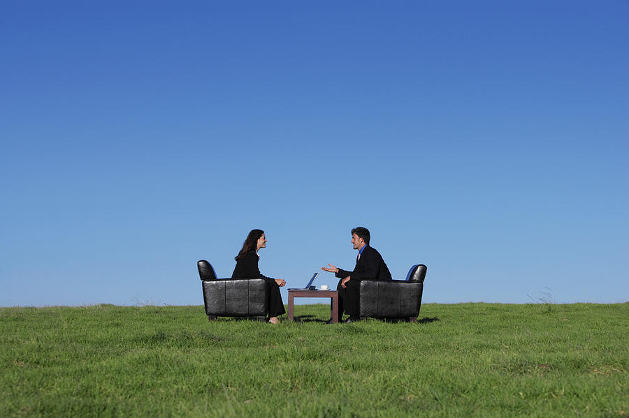 Two Business Executives Sitting in Armchairs on the Grass Talking to One Another Photograph by Digital Vision.