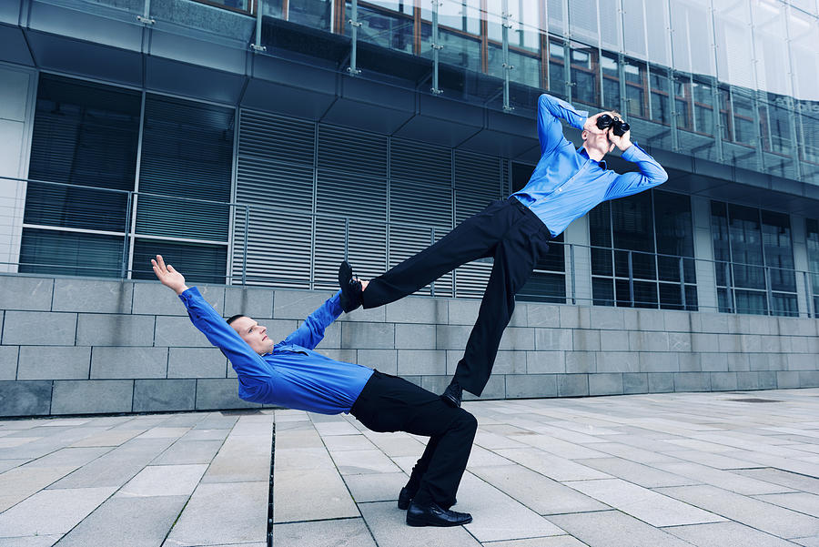 Two businessmen performing an acrobatic stunt together Photograph by Mikkelwilliam