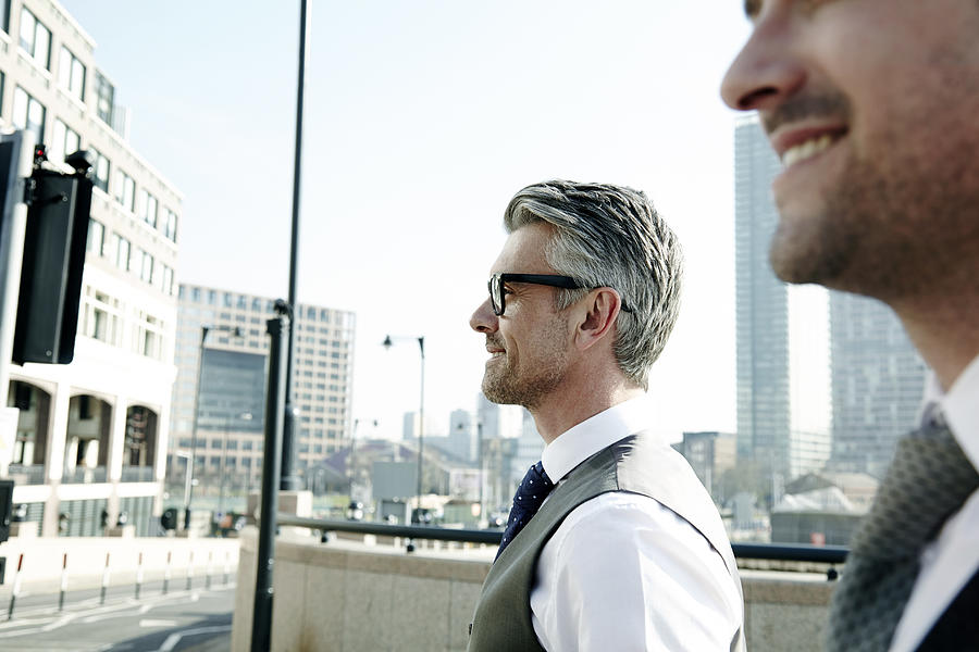 Two businessmen talking on the move, in the city. Photograph by Ezra Bailey