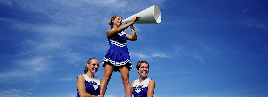 Two cheerleaders supporting third cheerleader with megaphone Photograph by Yellow Dog Productions