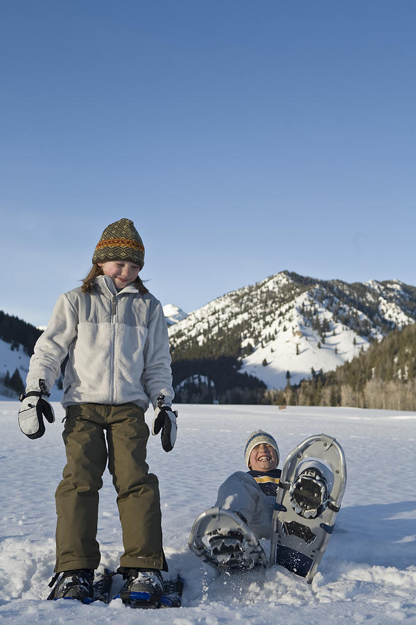 Two children (9-10) walking in snowshoes in mountains, laughing Photograph by Caroline Woodham
