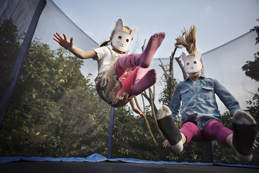 Two children wearing rabbit masks and bouncing on a trampoline Photograph by Elva Etienne