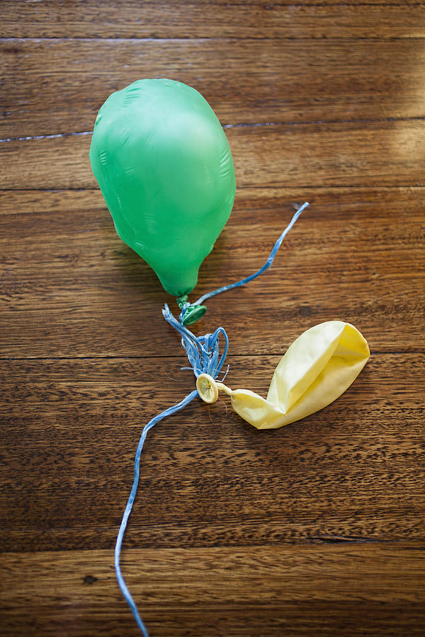Two deflated balloons on a wooden table Photograph by Tobias Titz