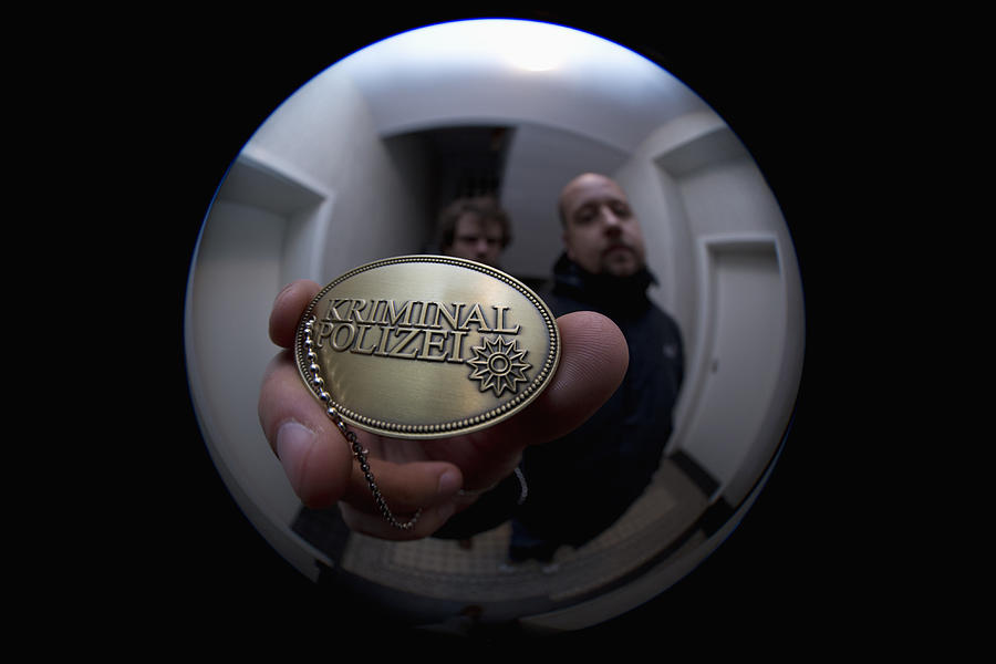 Two detectives showing a crime police (German: Kriminal Polizei) badge to a peephole Photograph by Caspar Benson