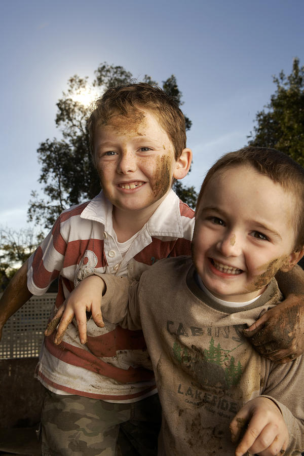 Two dirty boys (6-7, 8-9)  playing outdoors, portrait Photograph by Steve Baccon