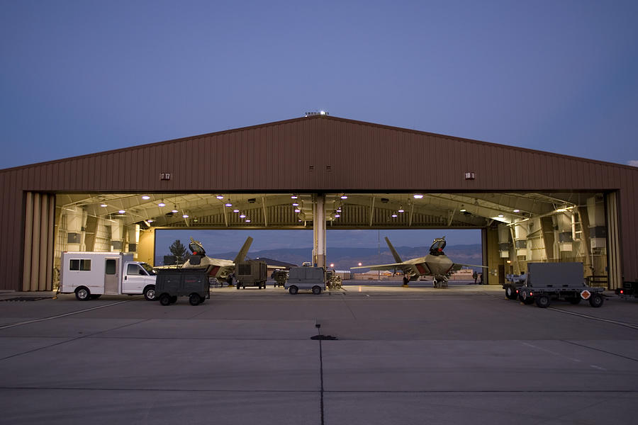Two F-22 Raptors sit in their hangars while maintenance crews work on them between sorties at Holloman Air Force Base, New Mexico. Photograph by HIGH-G Productions/Stocktrek Images
