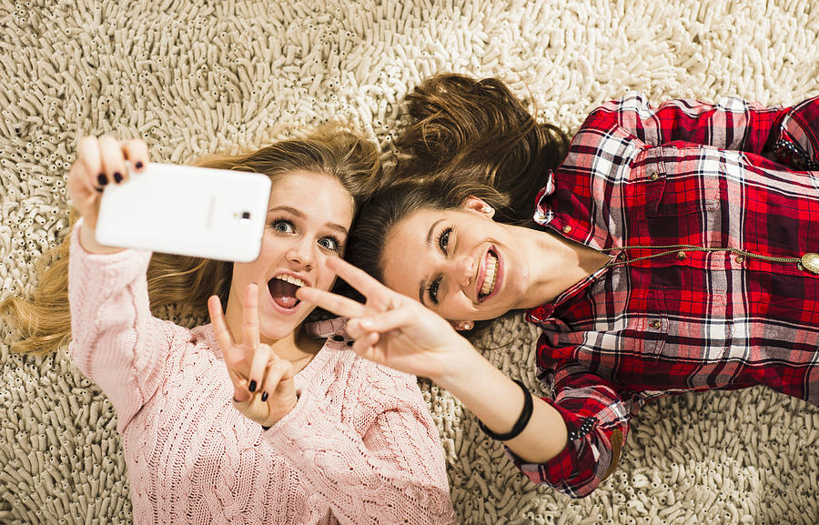 Two female friends taking a selfie with smartphone at home Photograph by Westend61