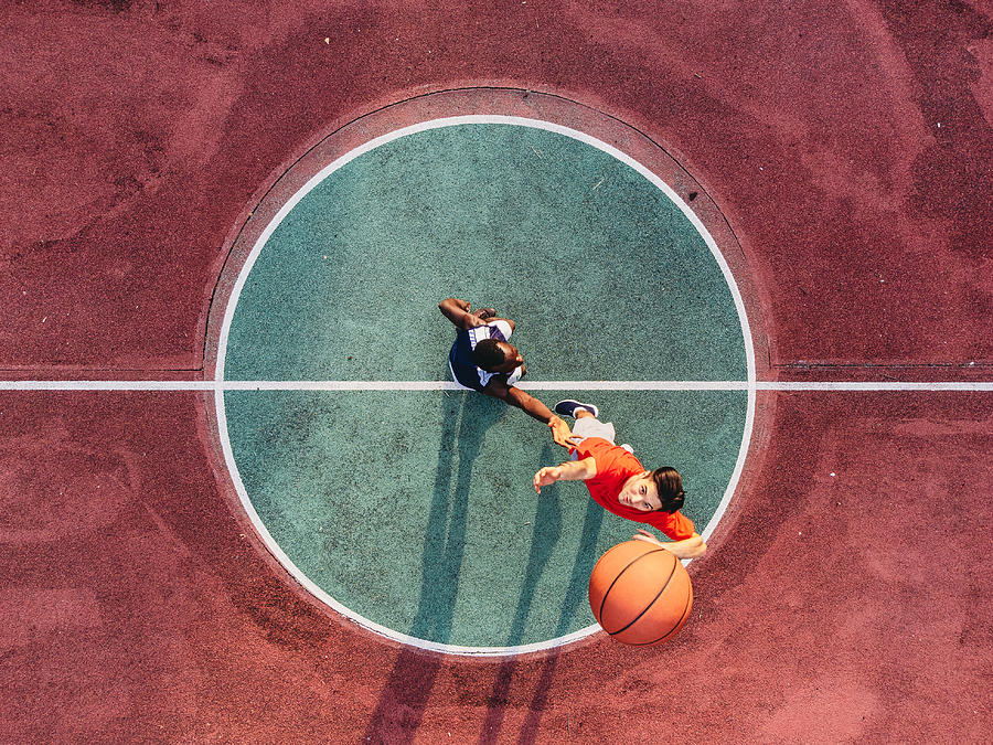 Two friends are jumping to take a basketball ball on the center field Photograph by FilippoBacci