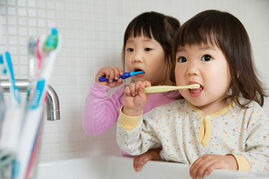 Two girl toddlers brushing teeth at bathroom sink Photograph by Igor Emmerich