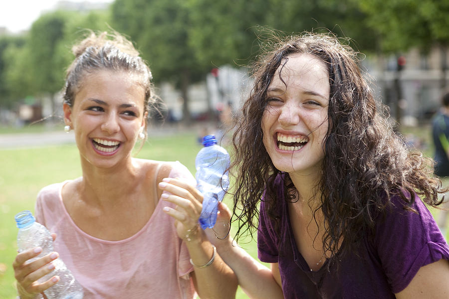 Two girls having fun with water in a park Photograph by Vincent Besnault