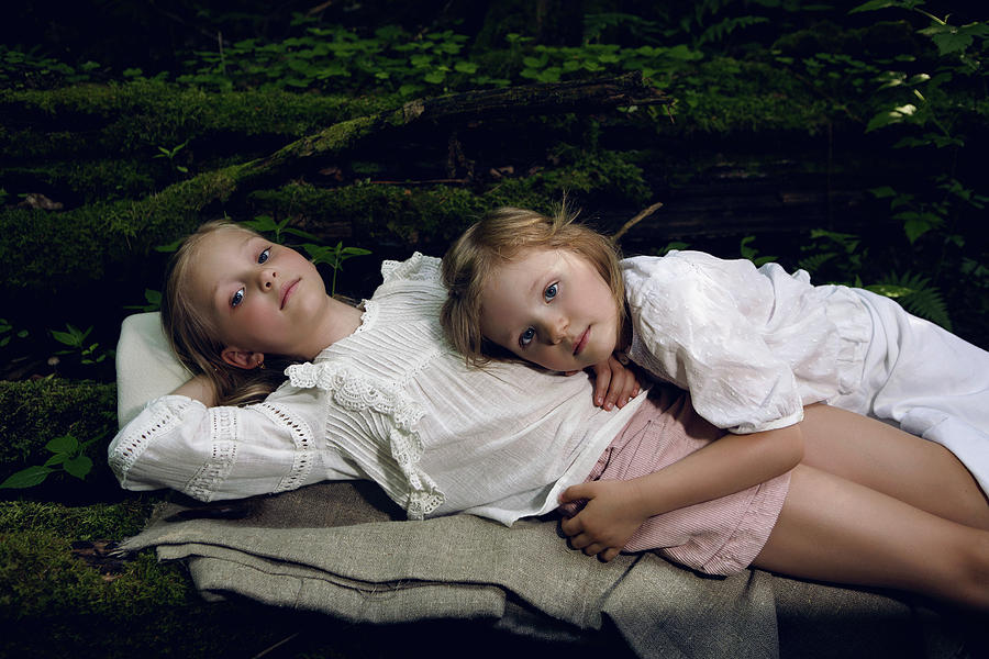Two Girls Sisters In White Dresses Lie On Logs Photograph